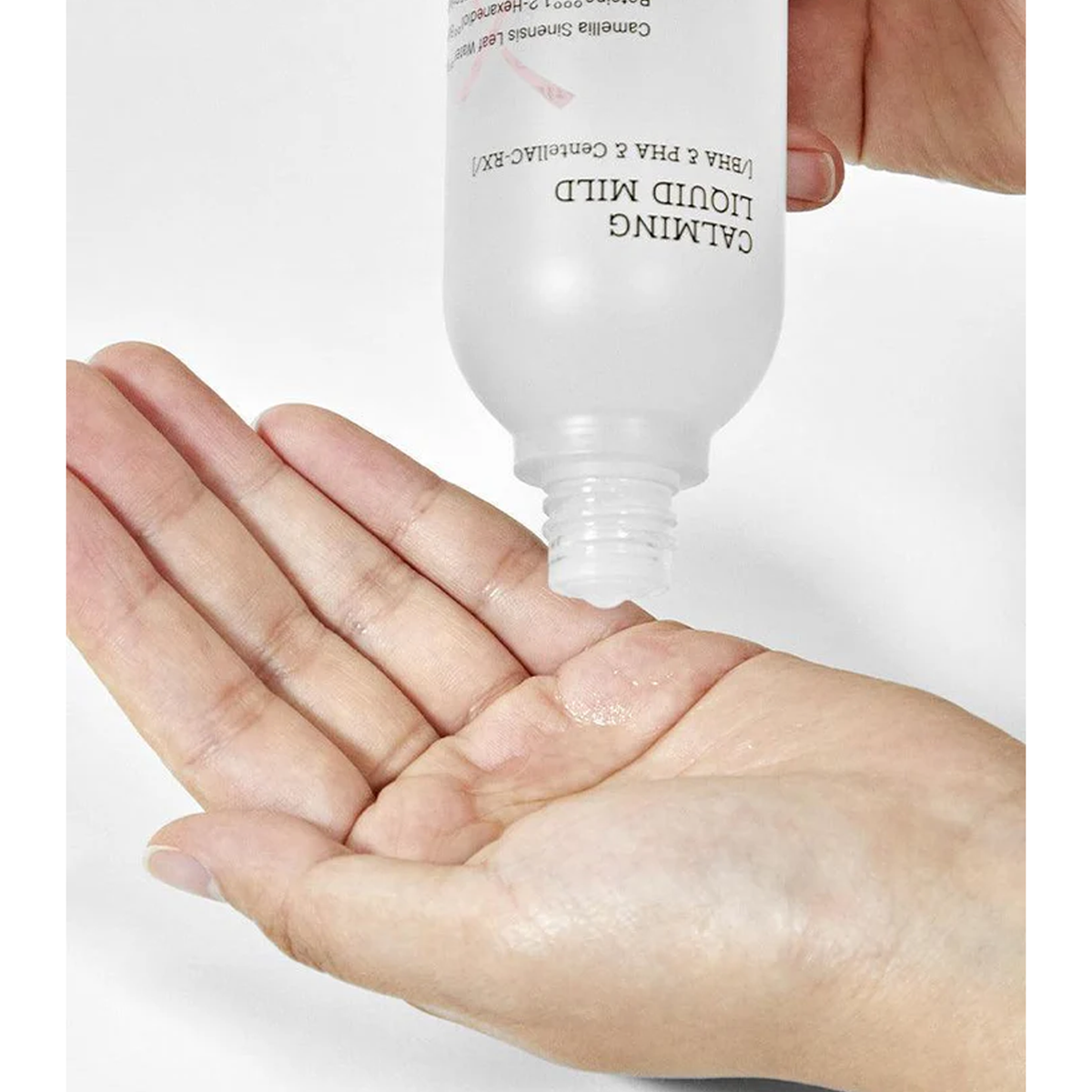 A hand grasping a bottle labeled AC Collection Calming Liquid Mild, designed for skincare and acne prevention.